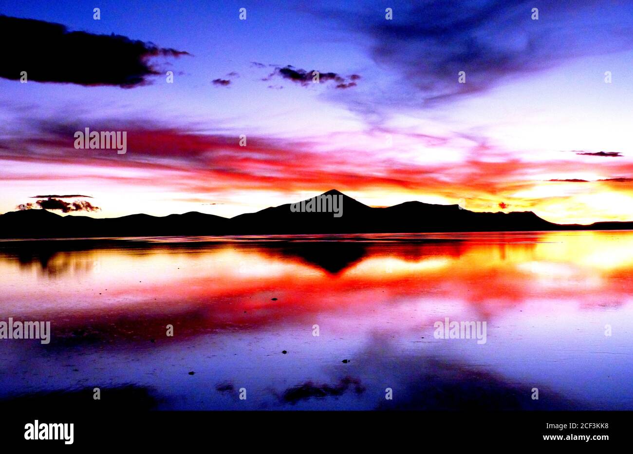 Beeindruckende surreale Landschaft von Salar de Uyuni, Bolivien. Dramatischer Sonnenuntergang Himmel. Toller roter Sonnenuntergang über dem Salzsee. Himmel Spiegelung im Wasser Stockfoto