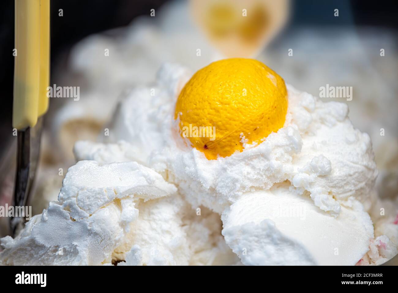 Makro Nahaufnahme von Zitrone Geschmack gelbe Früchte und weiße Gelato Eis mit Schaufel auf dem Display in Café-Shop in Italien, Italienisch Stockfoto