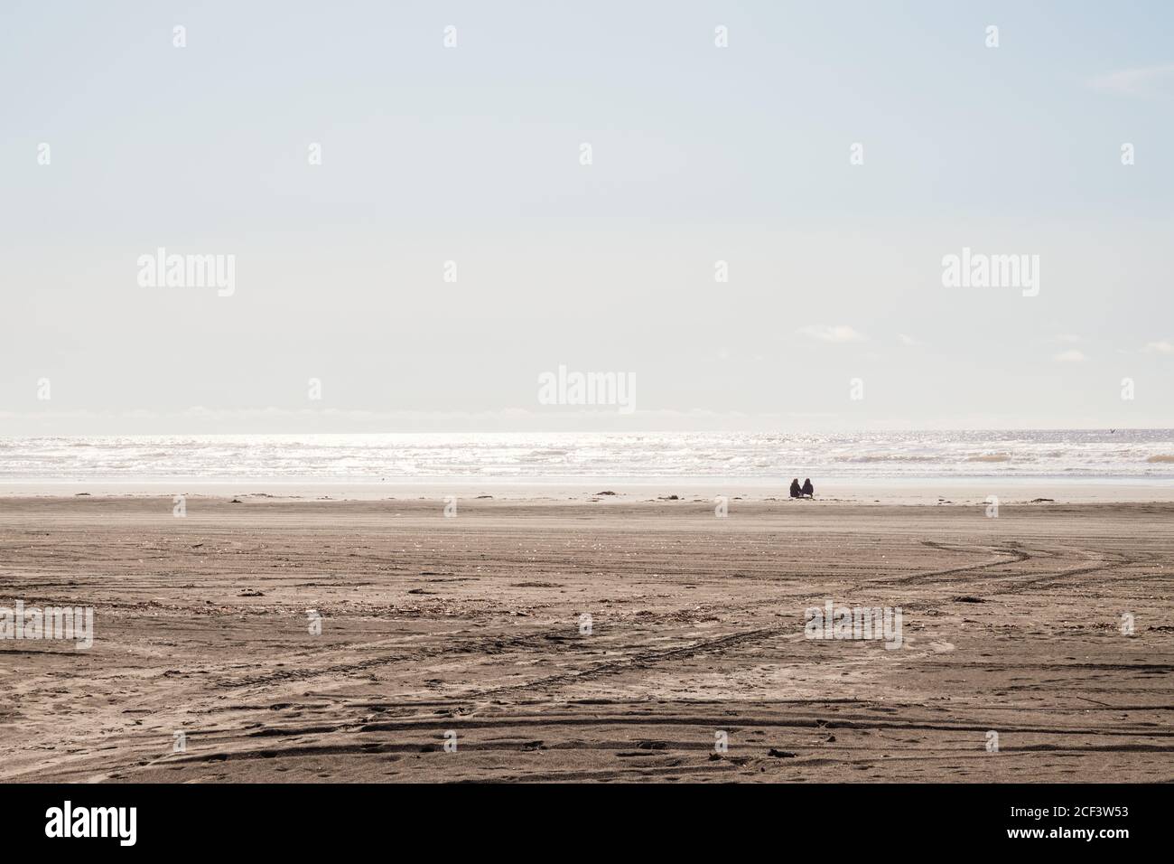 Zwei Personen sitzen allein am Ocean Beach an einem hellen, sonnigen Tag Stockfoto