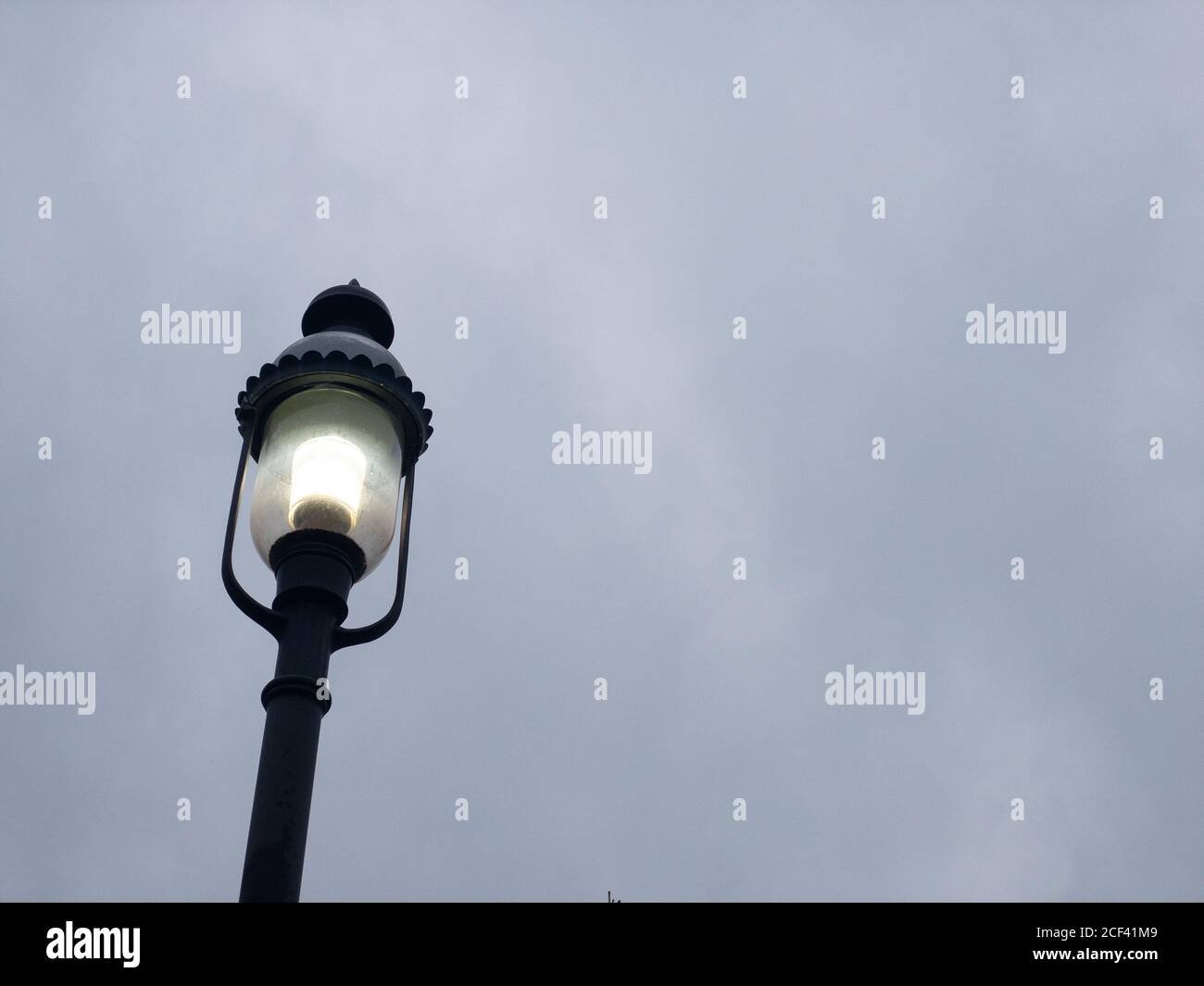 Eine altmodische schwarze Metall-Straßenleuchte auf einem Grau Bedecktem Himmel Stockfoto