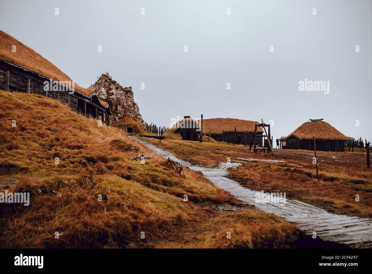 Alte Hütten auf einem Hügel mit trockenem Gras Gegen grauen Himmel Stockfoto