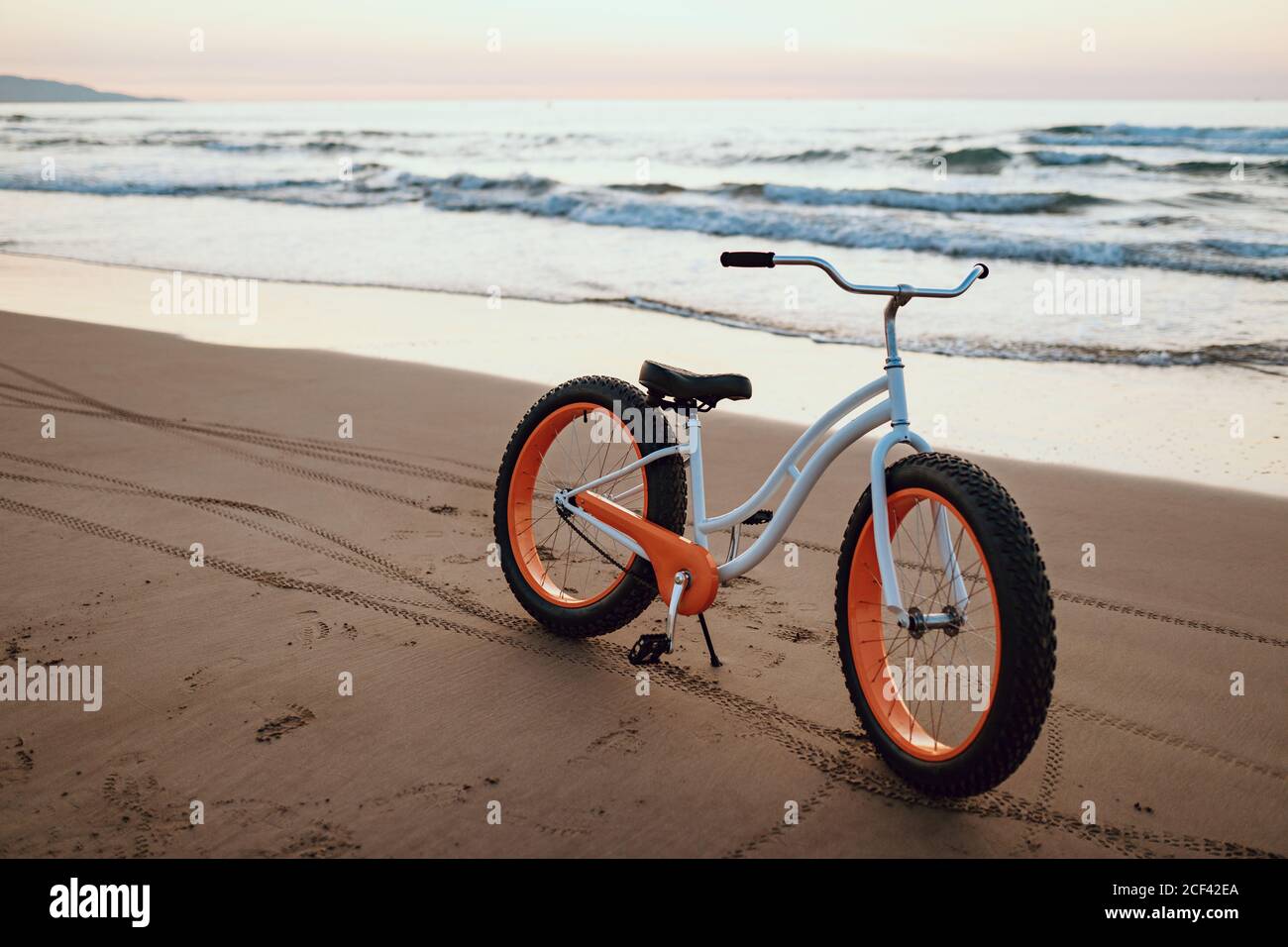 Modernes fetter Fahrrad, das am Strand am Sonnenuntergang geparkt wird Stockfoto