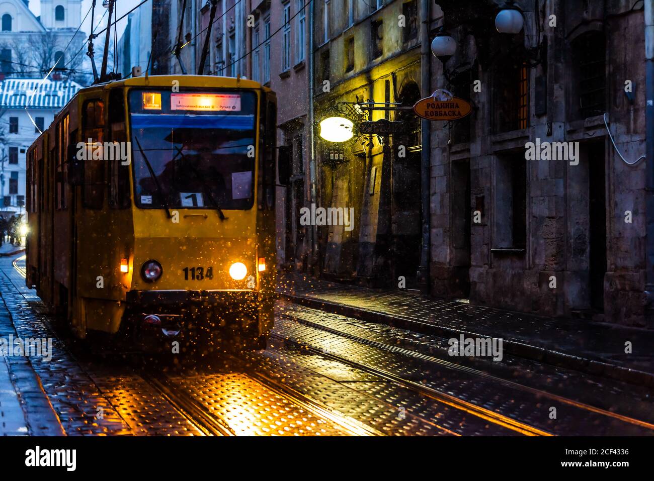 Lviv, Ukraine - 28. Dezember 2019: Altstadtallee in Lvov mit Winterschnee in dunkler Abendnacht und Straßenbahnscheinwerfern beleuchtet gelbe Farbe Stockfoto