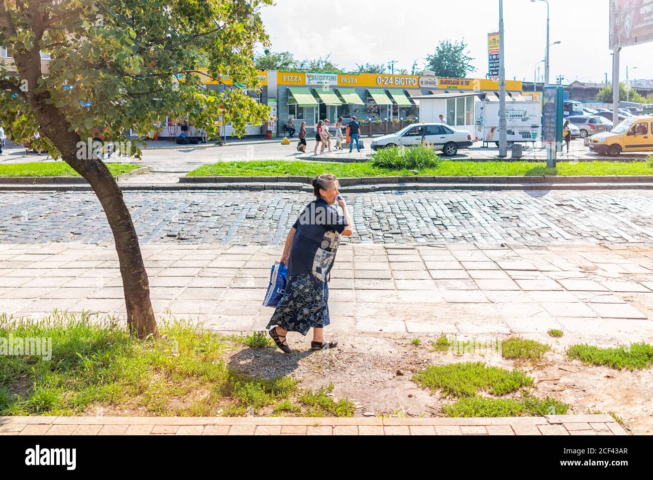 Lviv, Ukraine - 1. August 2018: In der Nähe des Bahnhofs Lvov mit einer alten Frau, die im Sommer auf der Straße in der historischen ukrainischen Stadt spazieren geht Stockfoto