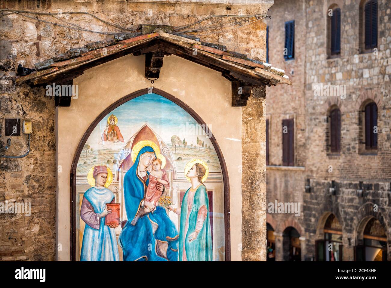 San Gimignano, Italien - 27. August 2018: Straße in historischen mittelalterlichen Altstadt Dorf in der Toskana mit niemand und religiösen Wandbild mit Jungfrau Maria und J Stockfoto