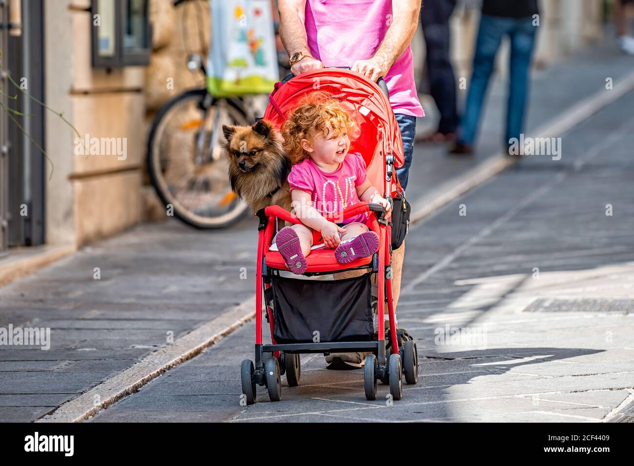 Assisi, Italien - 29. August 2018: Menschen Touristen auf der Straße mit Baby Kind und Hund lustig zusammen in Kinderwagen in Umbrien Stadt Dorf Stockfoto
