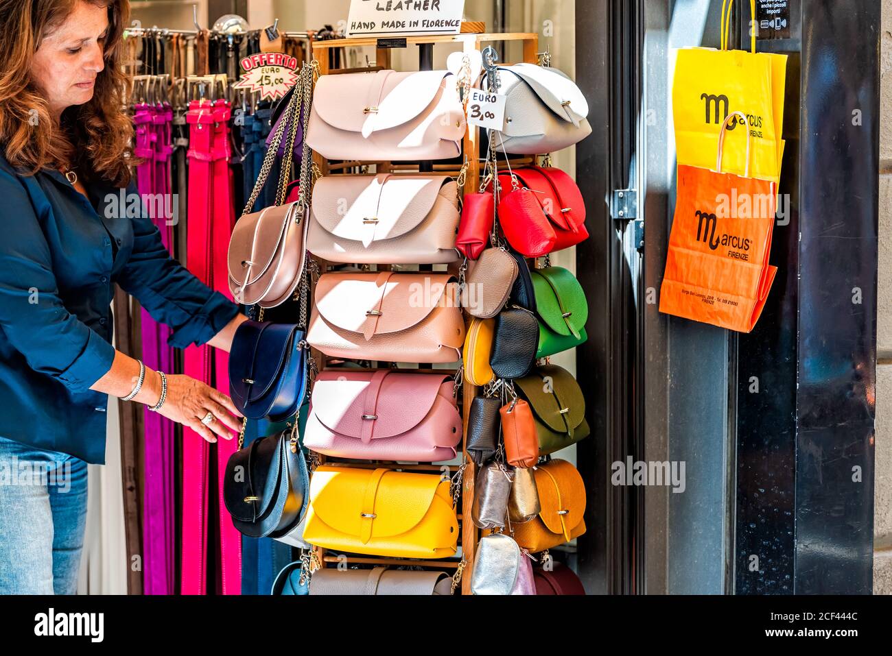 Florenz, Italien - 30. August 2018: Viele Ledertaschen bunte lebendige hängen auf dem Display in Shopping-Markt in Florenz in der Toskana mit Frau kaufen Stockfoto