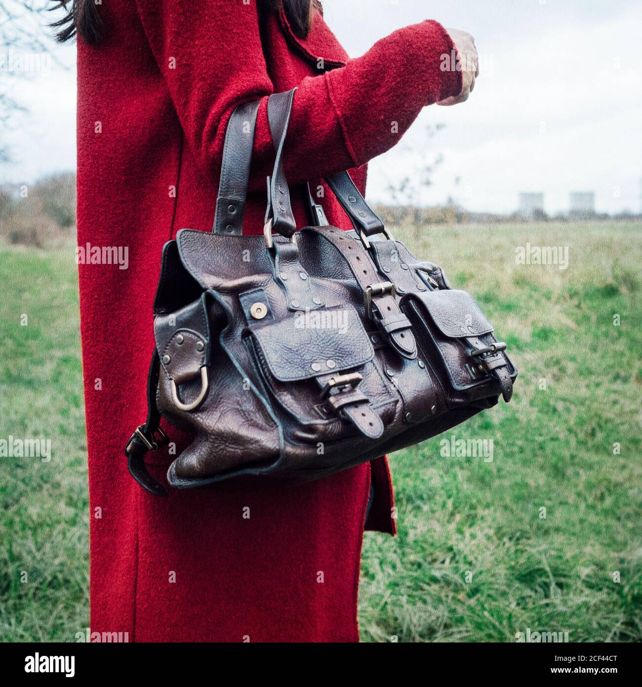 Frau im roten Mantel hält eine Mulberry Roxanne Lederhandtasche Stockfoto
