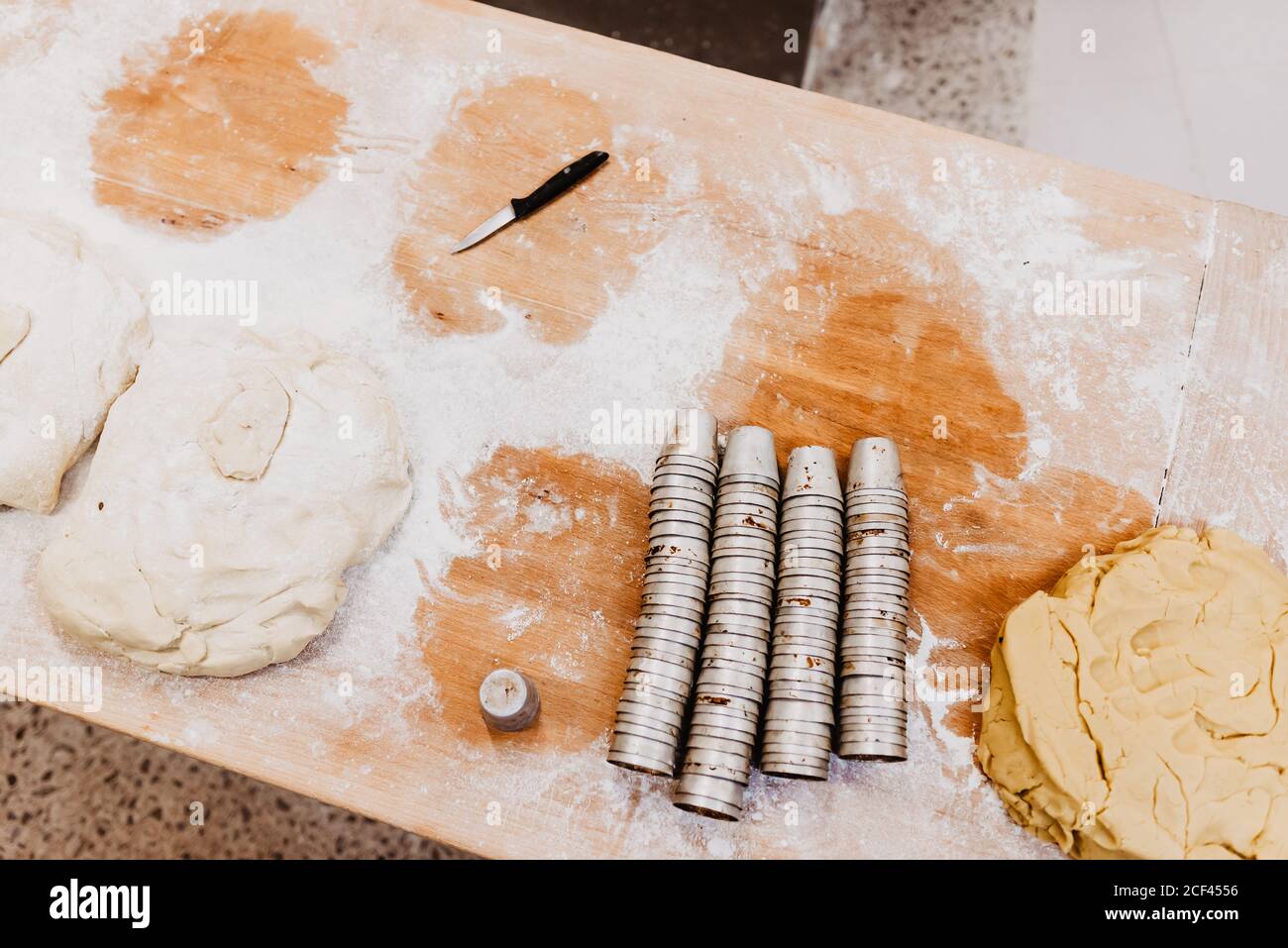 Von oben kleines Messer und Satz von Tassen auf gelegt Bemehlter Tisch in der Bäckerei Stockfoto