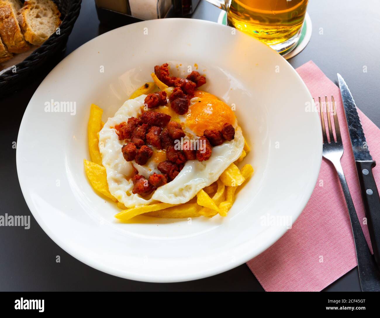 Appetitlich gebratene Eier serviert mit beliebten spanischen Chistorra Wurst und Pommes Stockfoto