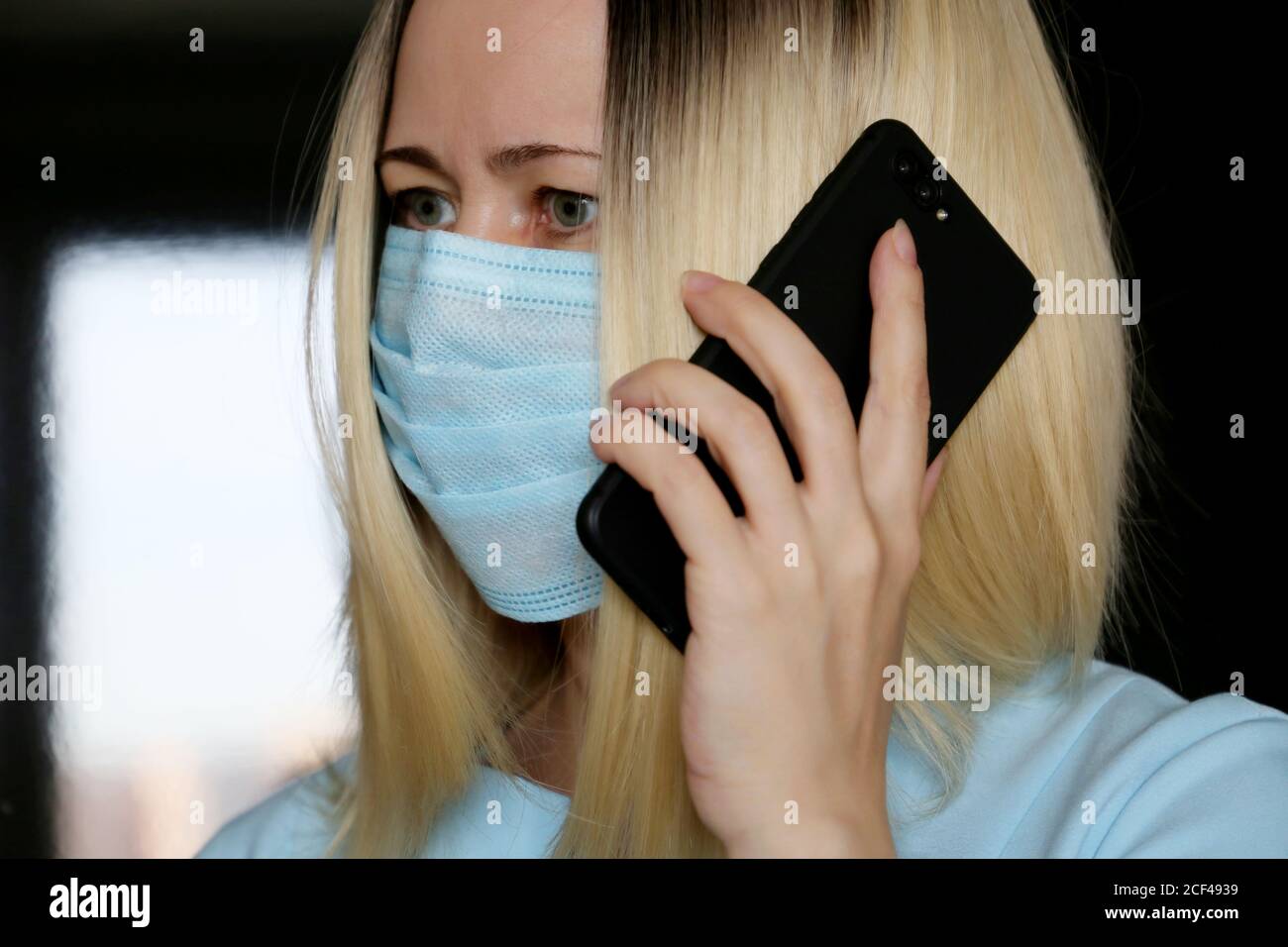 Portrait der blonden Frau in Gesichtsmaske sprechen auf dem Handy, Smartphone in der weiblichen Hand Nahaufnahme. Konzept der Kommunikation während des Coronavirus Stockfoto