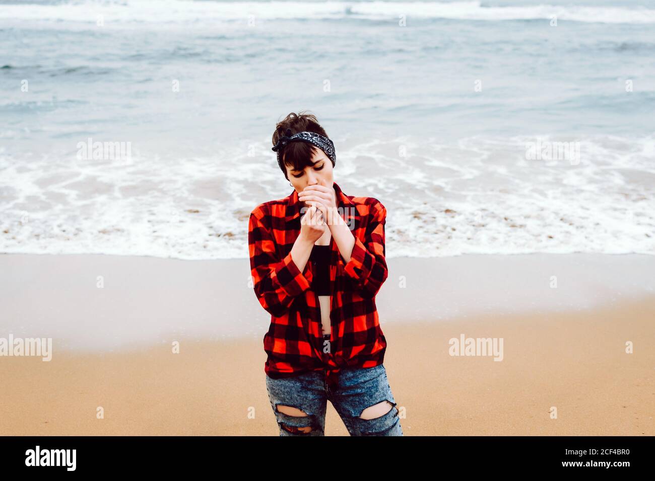 Frau zündete Zigarette am Strand an Stockfoto