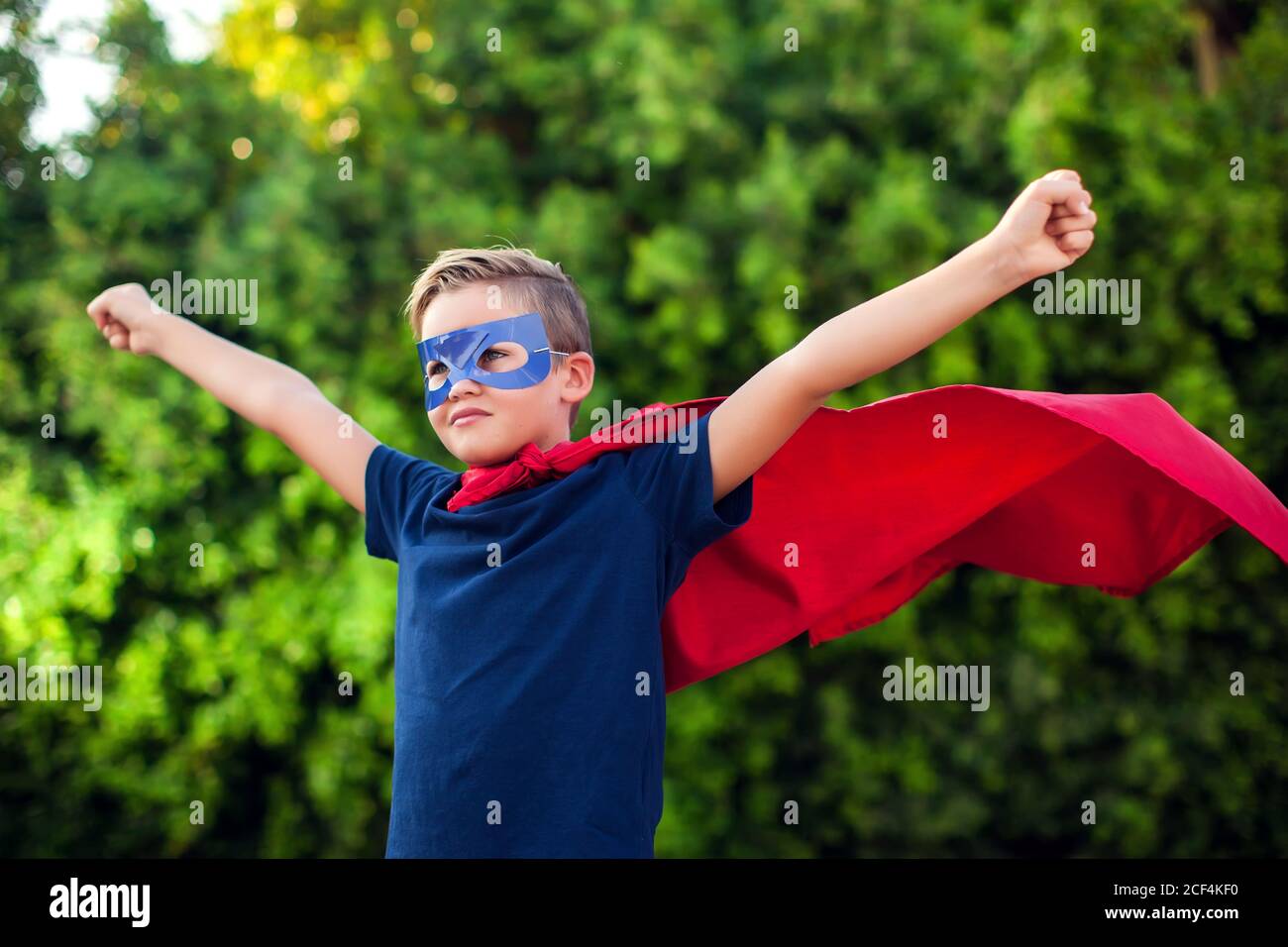 Superheld Kind Junge vor grünem Hintergrund im Freien. Kindheit, Erfolg und Machtkonzept Stockfoto