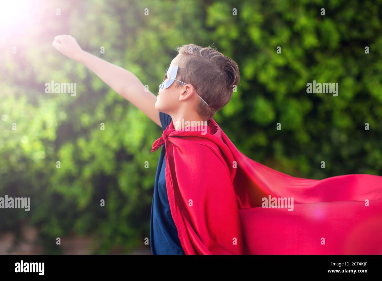 Superheld Kind Junge vor grünem Hintergrund im Freien. Kindheit, Erfolg und Machtkonzept Stockfoto