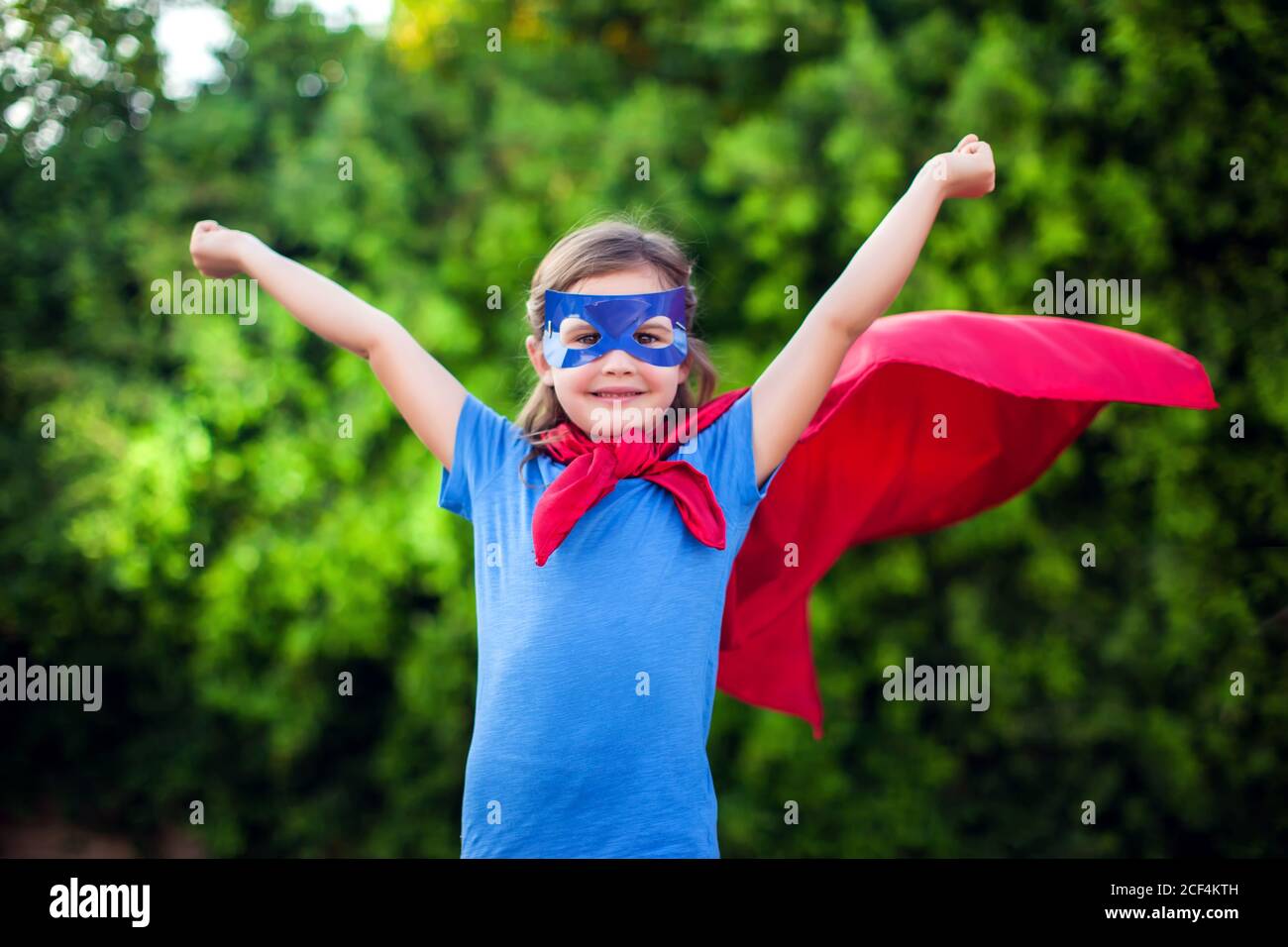 Superheld Kind Mädchen vor grünem Hintergrund im Freien. Kindheit, Erfolg und Machtkonzept Stockfoto