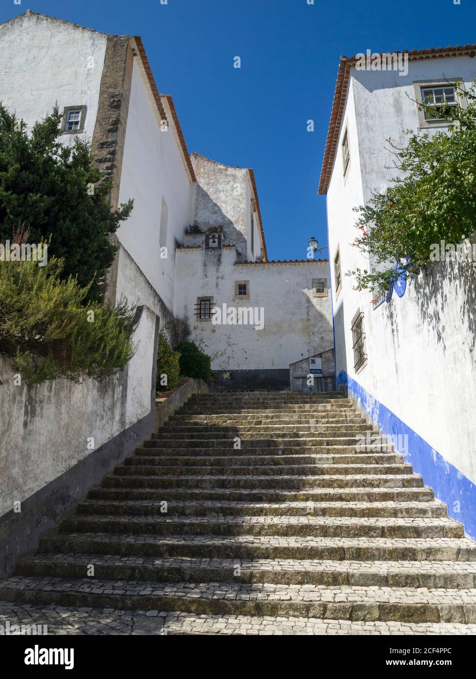 Straße und Gasse mit weiß gestrichenen Wänden im Dorf Óbidos in der Provinz Estremadura - Portugal. Stockfoto