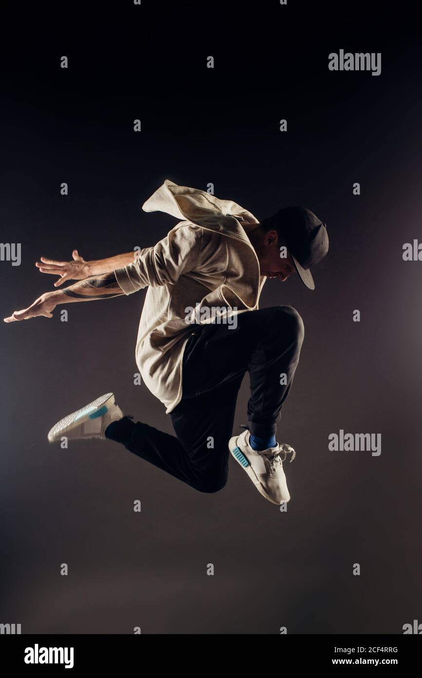 Springende junge männliche Tänzerin auf grauem Hintergrund Stockfoto