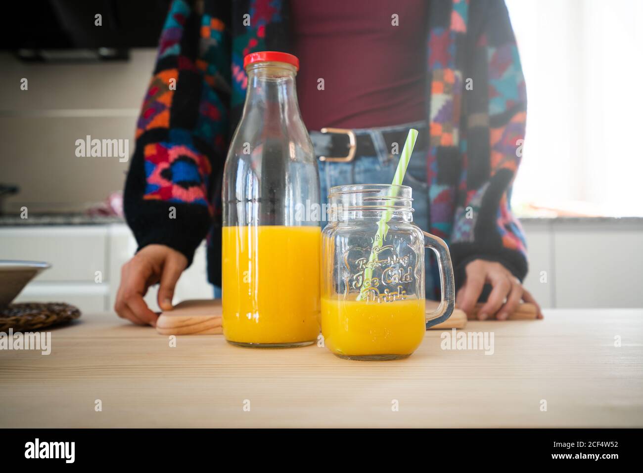 Glas mit leckeren frischen Orangensaft und Glas mit Stroh auf Holz-Tischplatte mit abgeschnitten Frau hinter platziert Stockfoto