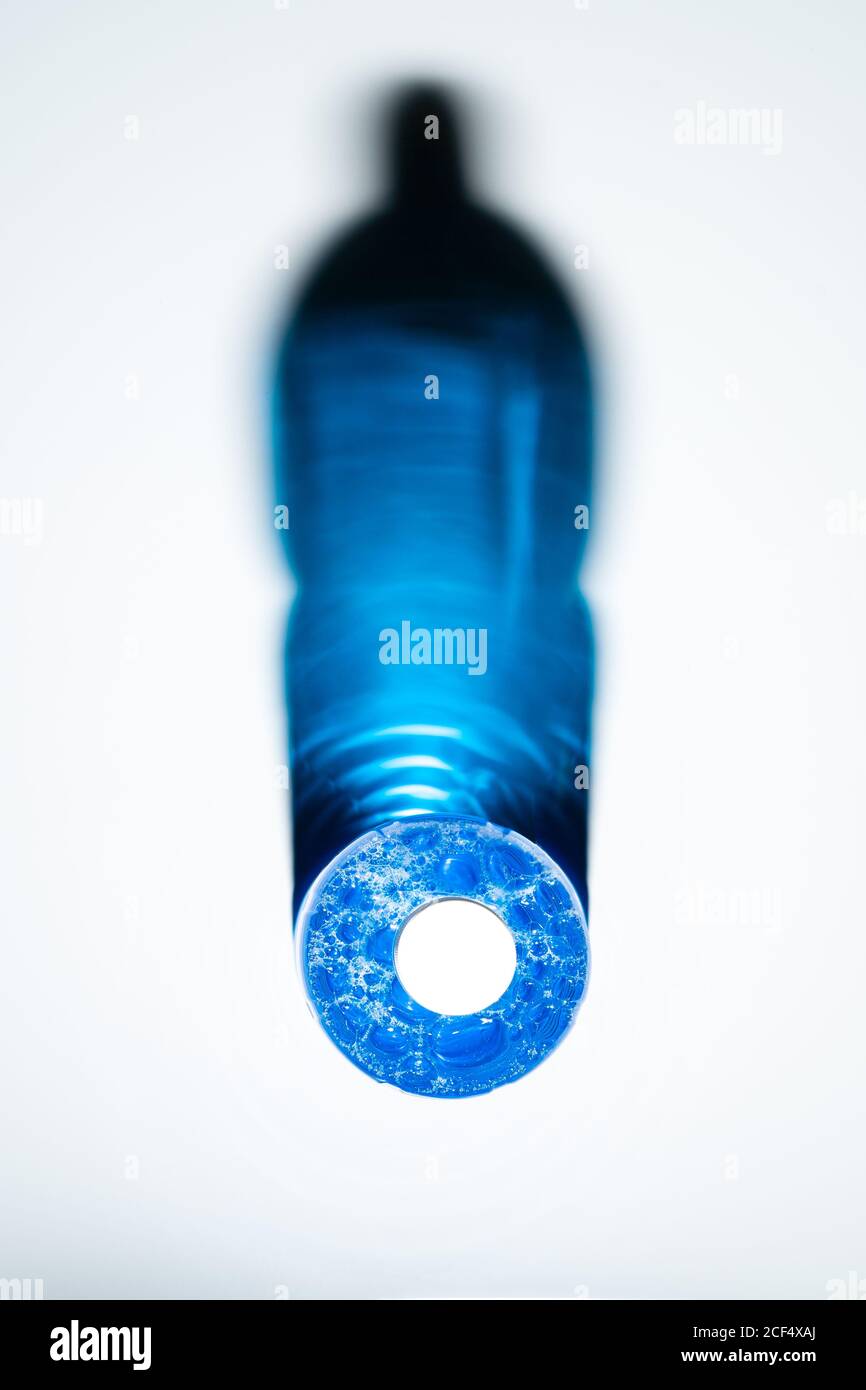 Draufsicht auf transparente Flasche mit blauer Seifenflüssigkeit reflektierend Leuchtende Kristallschatten auf weißer Oberfläche Stockfoto
