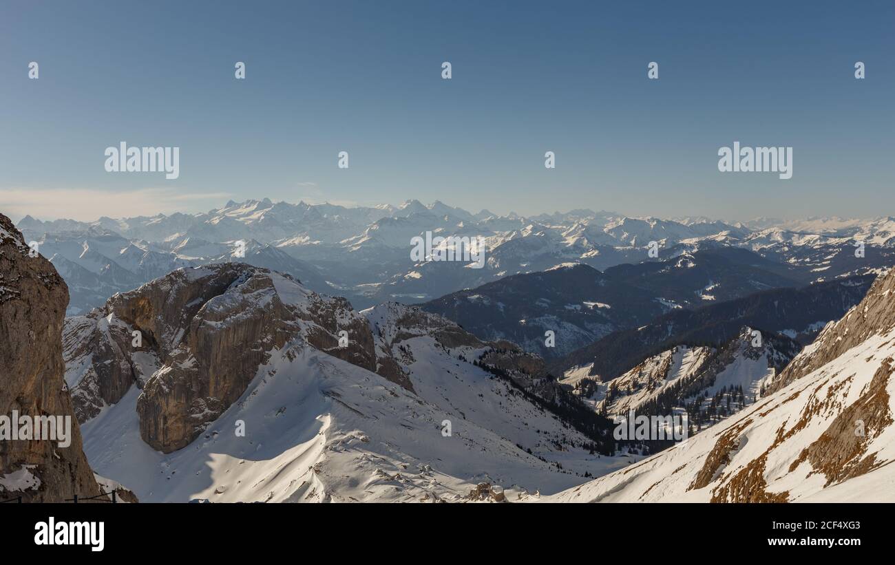 Panoramablick auf verschneiten Hang im Hintergrund von Bergen in Dunst und Sonnenlicht, Schweiz Stockfoto