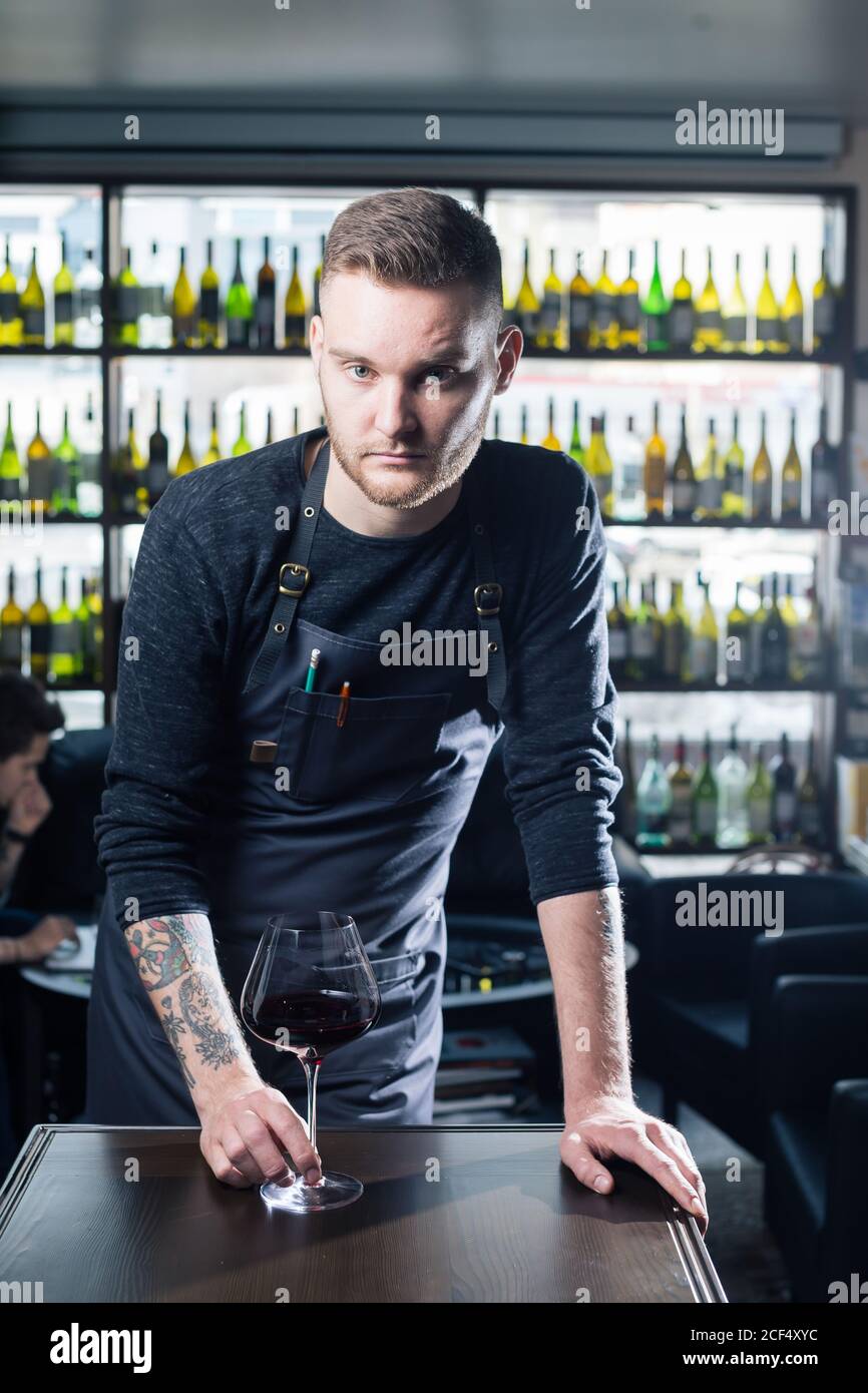 Porträt eines Sommeliers, der in einem Geschäft steht und ein Glas Wein hält und während einer Degustation den Daumen nach oben zeigt Stockfoto