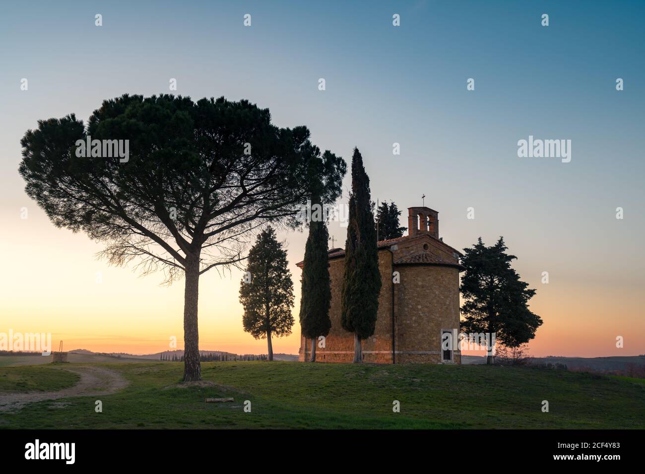 Schöne friedliche Landschaft von kleinen Kapelle mit Bäumen in abgelegenen leeren grünen Feld in der Toskana, Italien Stockfoto