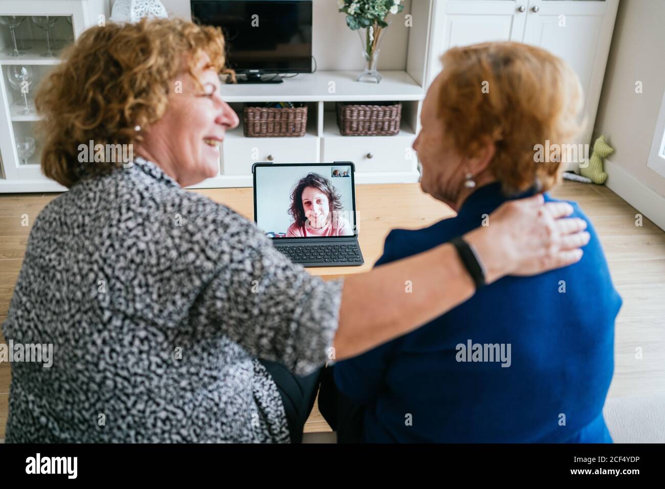 Rückansicht der fröhlichen älteren Frauen im Gespräch mit Freund während Online-Videotreffen über Laptop, während Sie zu Hause bleiben Coronavirus-Sperre Stockfoto