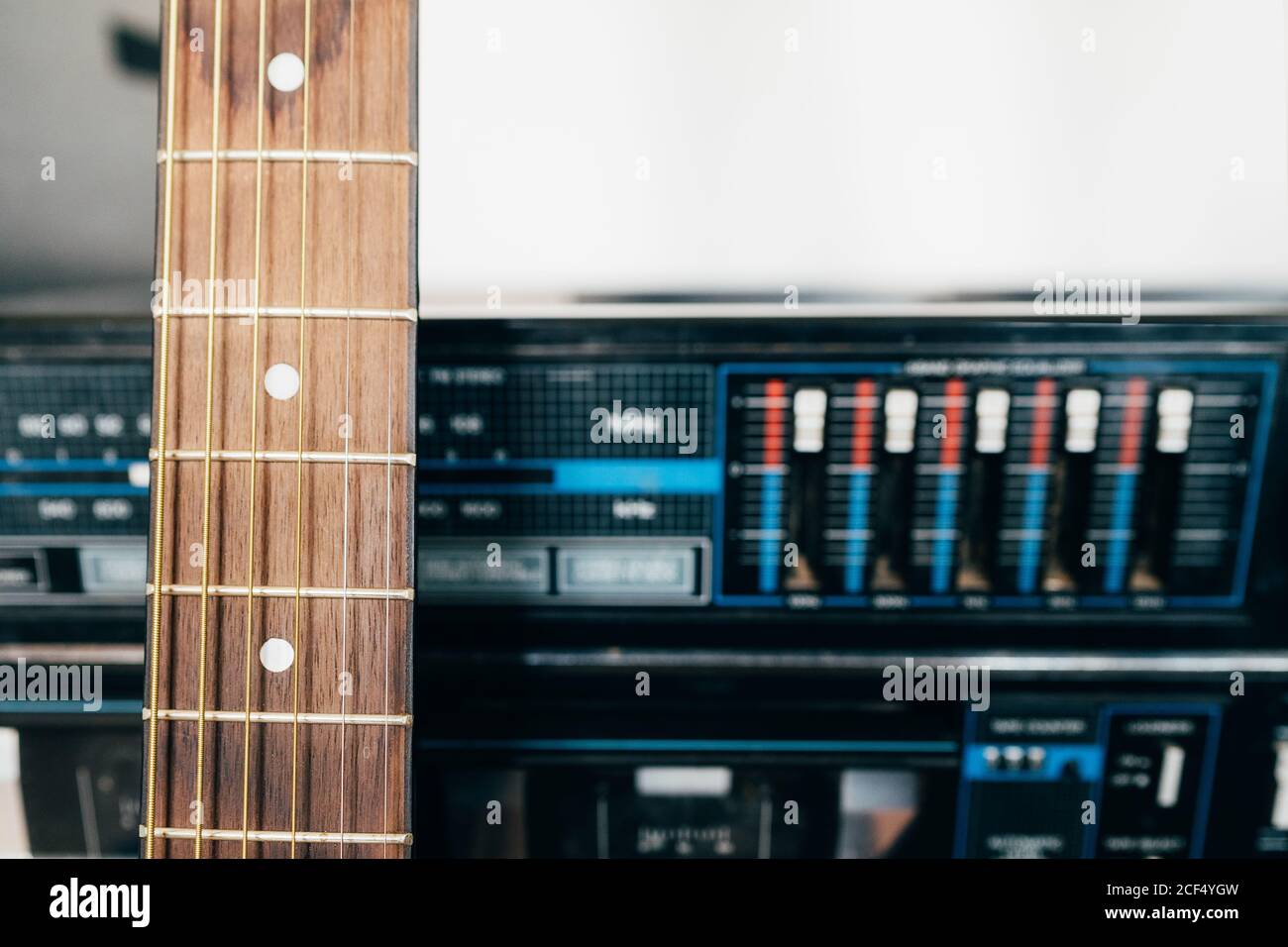 Der Hals einer braunen Holzgitarre ruht auf Ein antiker Plattenspieler Stockfoto