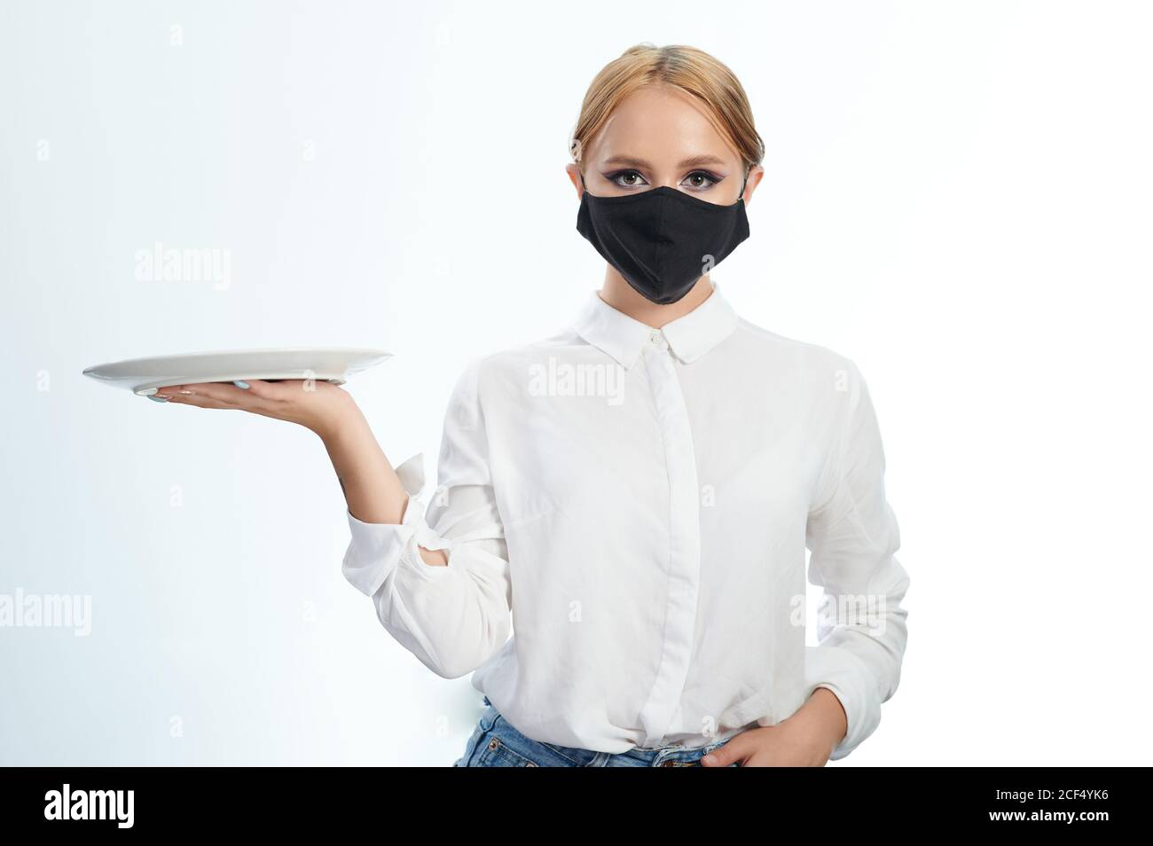 Kellnerin in Maske mit Teller in der Hand auf Seite isoliert Auf weißem Studiohintergrund Stockfoto