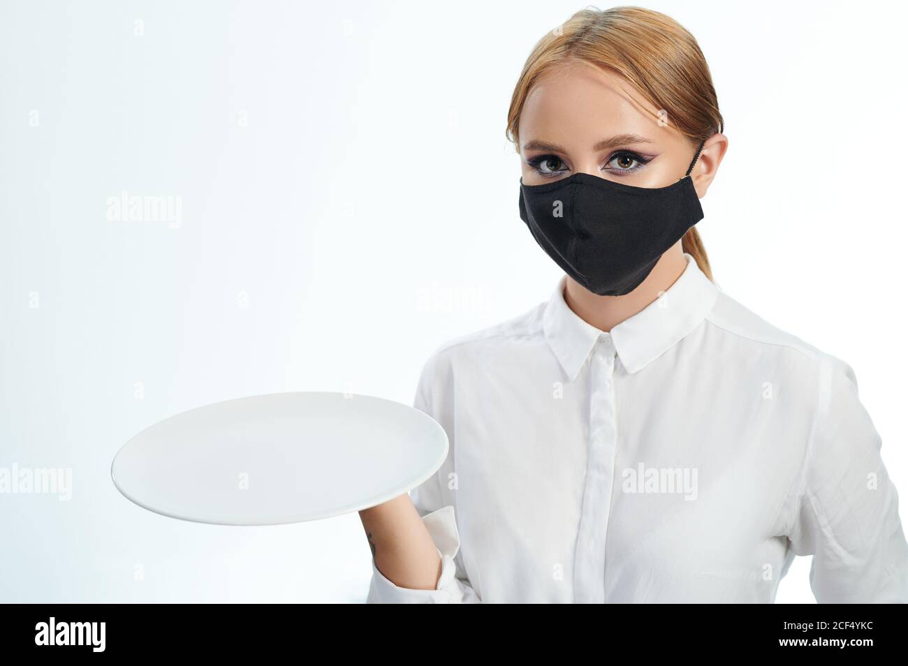 Junge Frau mit leerem Teller isoliert auf weißem Studiohintergrund Stockfoto