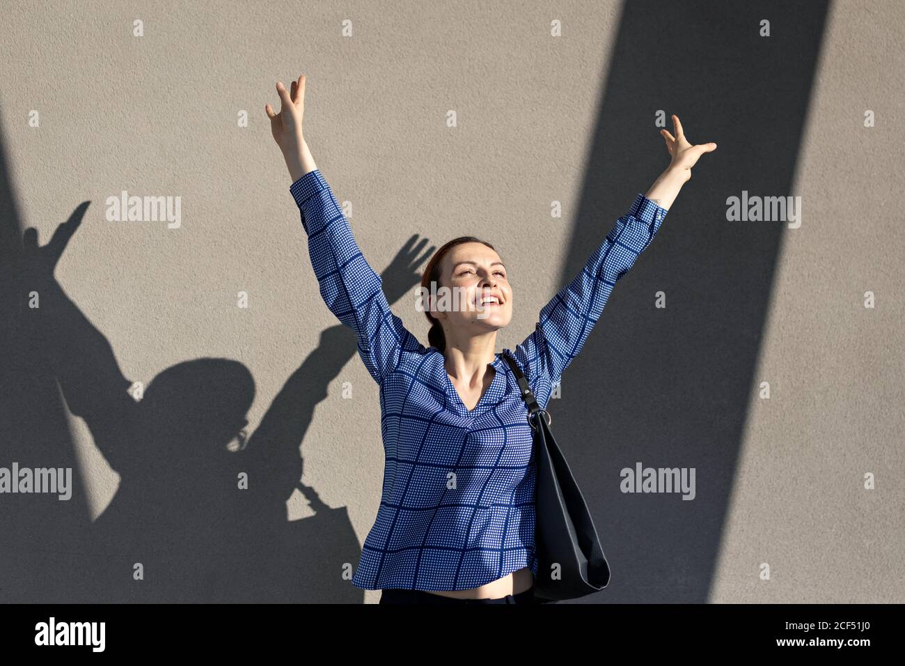 Weibliche Managerin in elegantem Outfit, die Arme hebt und springt Stockfoto