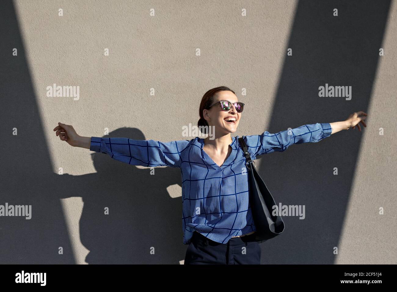 Weibliche Managerin in elegantem Outfit, die Arme hebt und springt Stockfoto