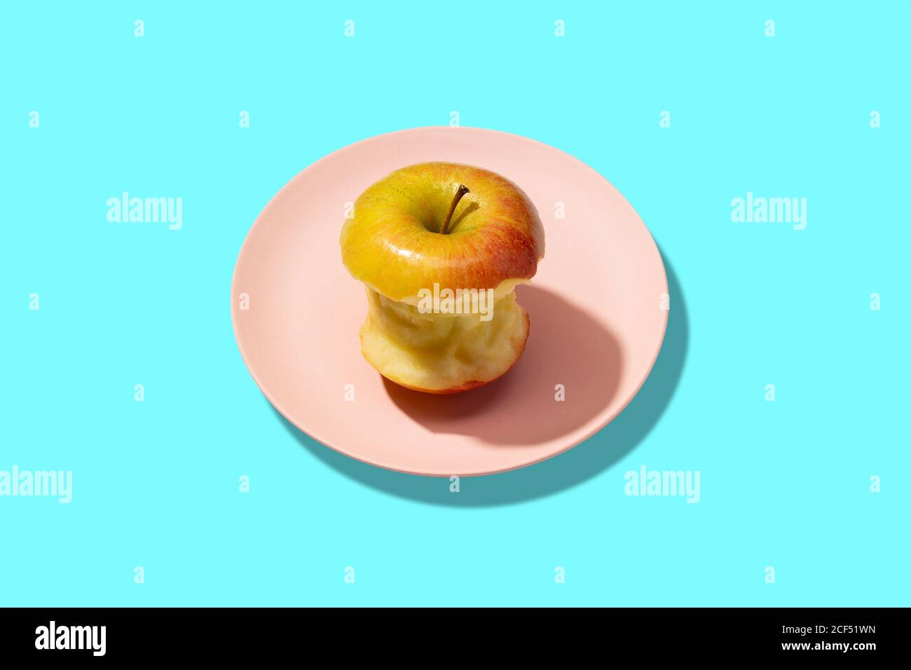 Frisch gebissen Apfel in Teller auf cyan Hintergrund. Lebhaft farbenfrohe Muster Stockfoto