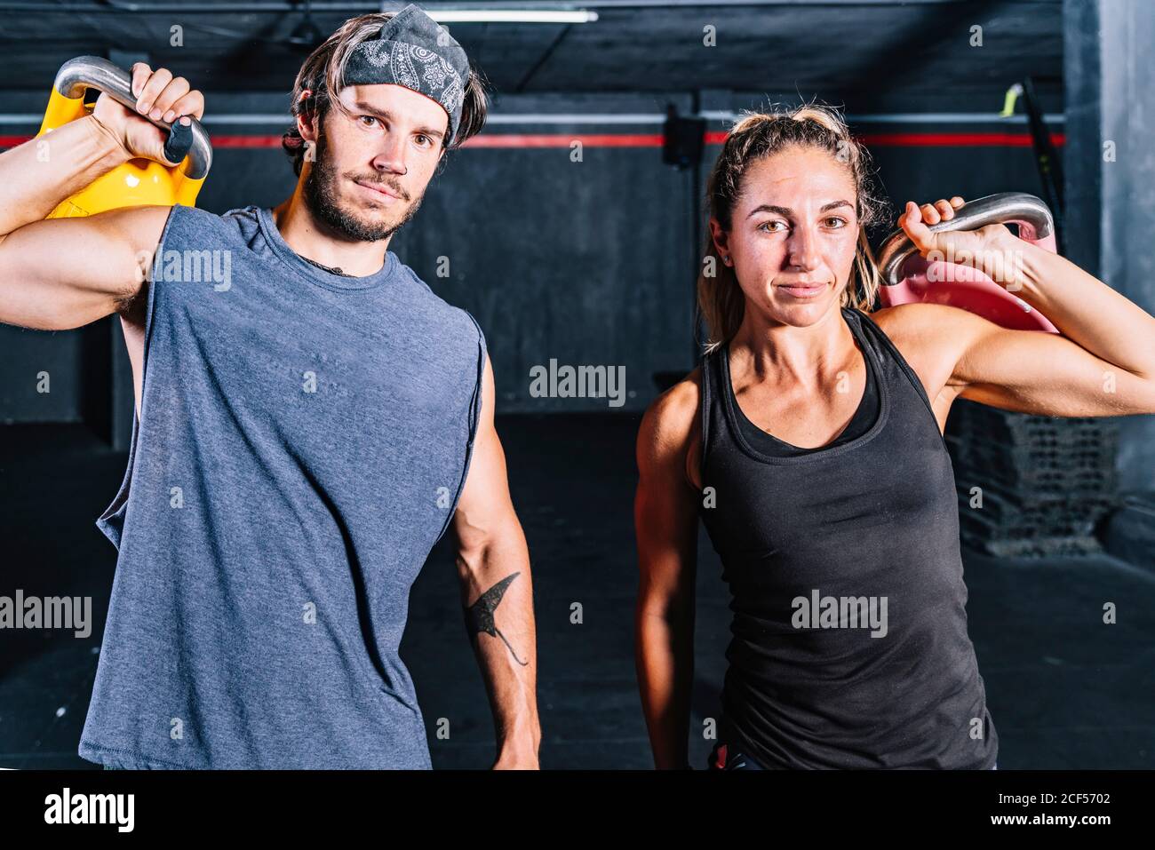 Muskulöse Gefährten mit Kettle Glocken Blick auf Kamera in zeitgenössischen Fitnesscenter Stockfoto
