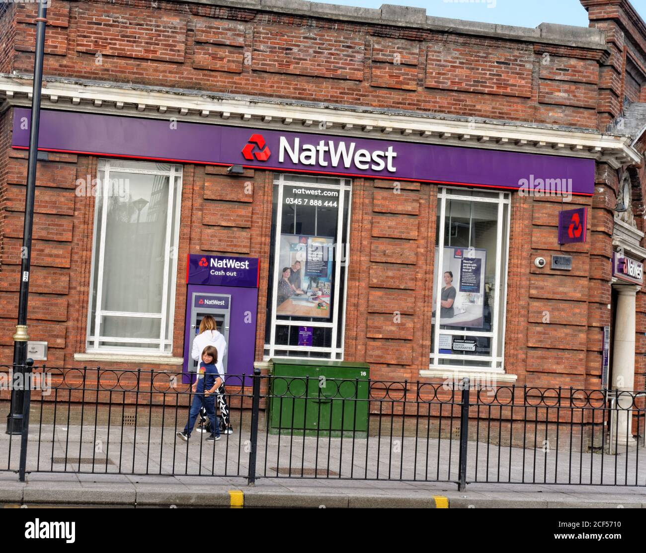 Eine Frau nutzt den Außenautomaten (Automated Teller Machine) bei einer NatWest Bank an der Bury New Road in Prestwich, Manchester, England. Stockfoto