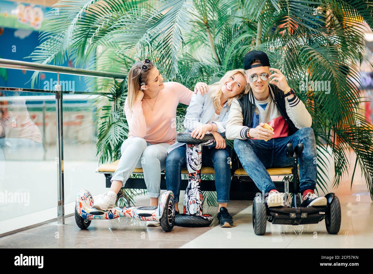 Gruppe der modernen Menschen mit elektrischen scooter Hoverboard an Bank sitzen und mit Hilfe von Phone Stockfoto