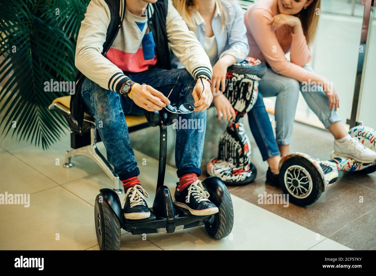 Gruppe der modernen Menschen mit elektrischen scooter Hoverboard an Bank sitzen und mit Hilfe von Phone Stockfoto