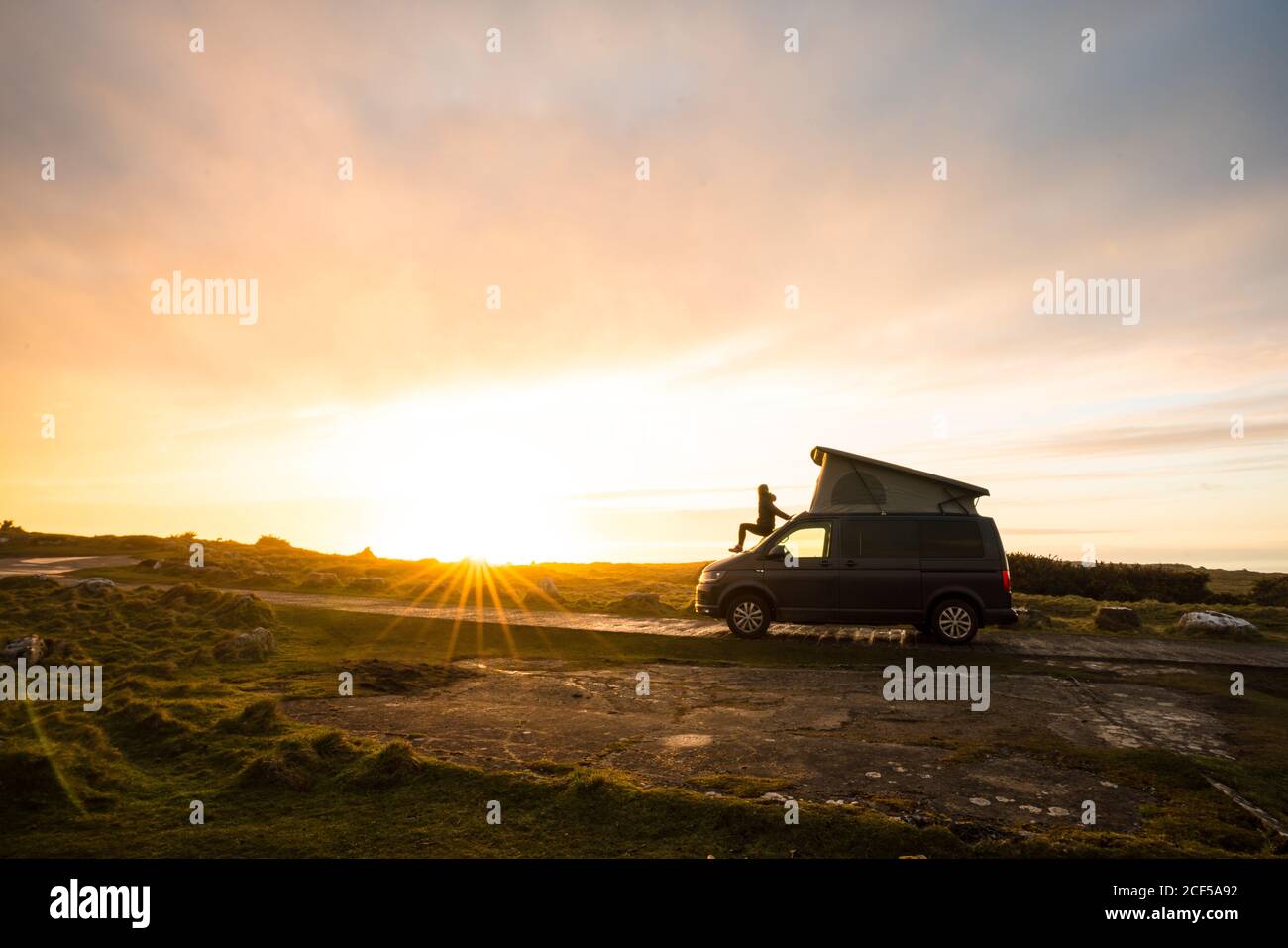 Mann Silhouette steht auf Wohnwagen Anhänger auf einsamen Landstraße bei Sonnenuntergang in Wales Stockfoto