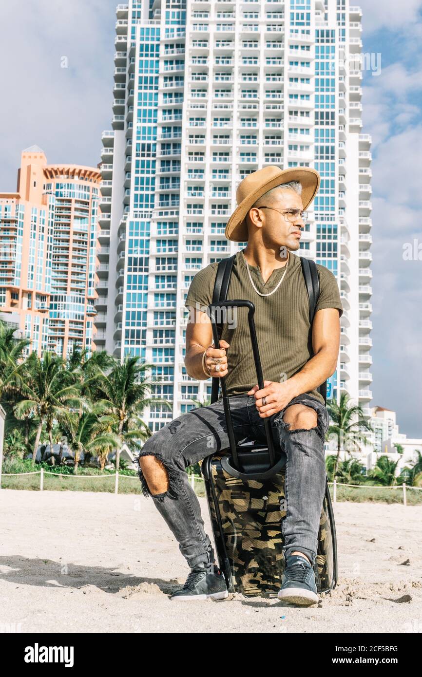 Der junge Mann, der am Strand im Resort ankommt, trägt einen Cowboyhut, ein T-Shirt, Jeans und geschlossene Schuhe. Stockfoto