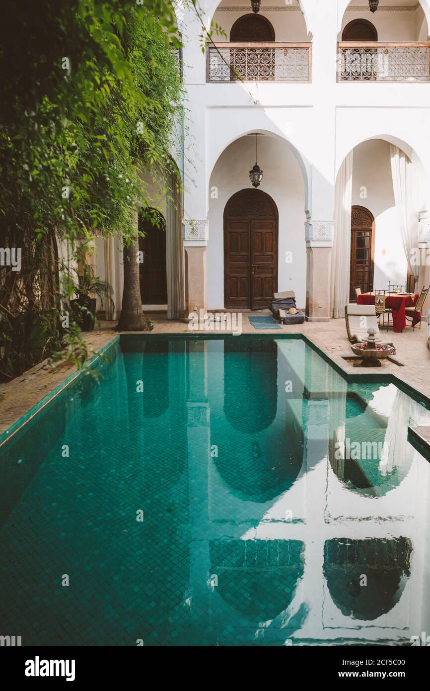 Friedliches klares Wasser des Pools auf der Terrasse des exotischen Resorts mit orientalischer Architektur in Sonnenlicht, Marokko Stockfoto