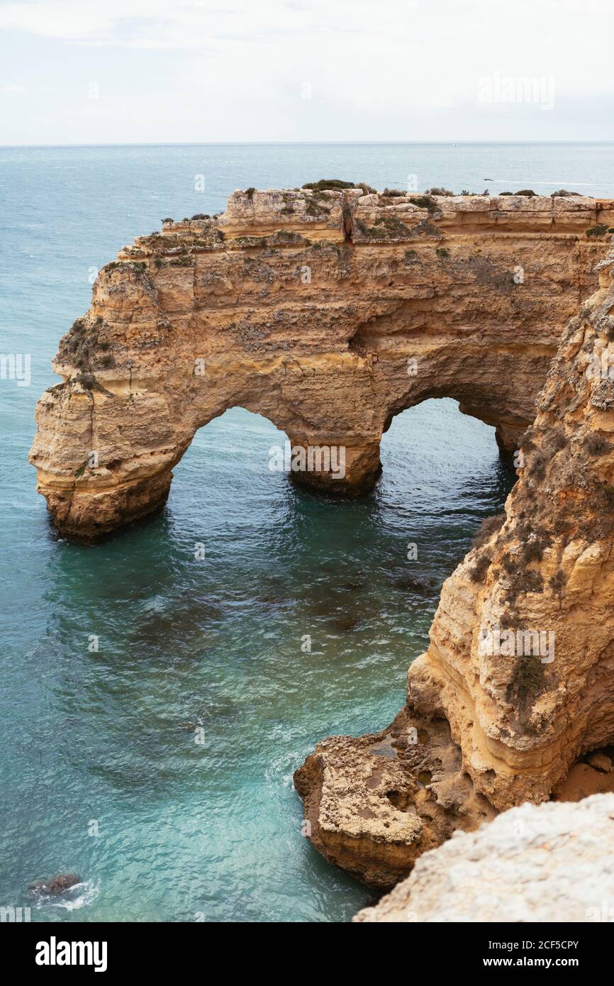 Sauberes Meerwasser plätschert in der Nähe gewölbte raue Klippe auf Ruhe Tag in Portugal Stockfoto