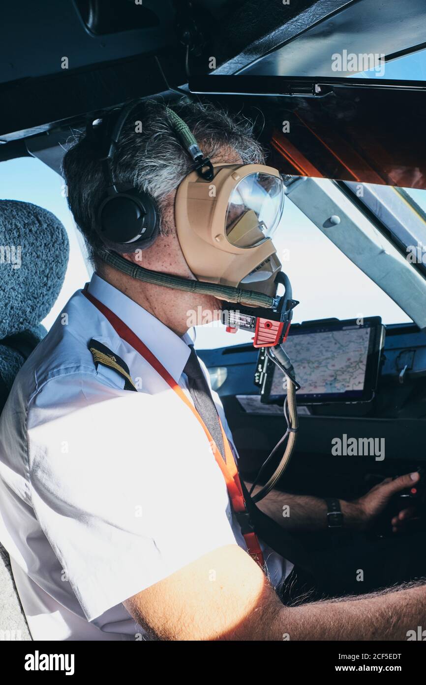 Pilot in Maske operierendes Flugzeug während des Fluges Stockfoto