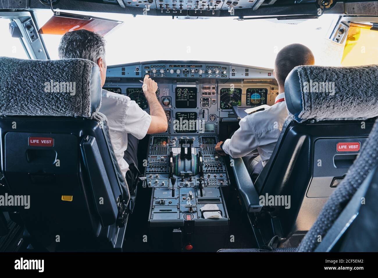 Rückansicht des männlichen Piloten und des CO-Piloten mit Instrument Panel im Cockpit der modernen Passagierflugzeuge während des Fluges Stockfoto