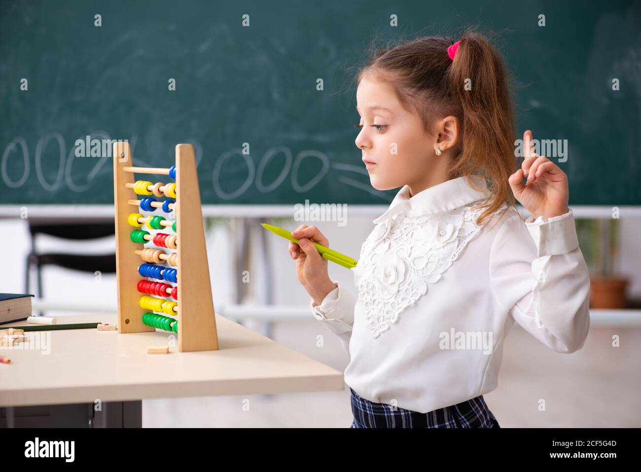 Kleines Mädchen vor der Tafel im Klassenzimmer Stockfoto