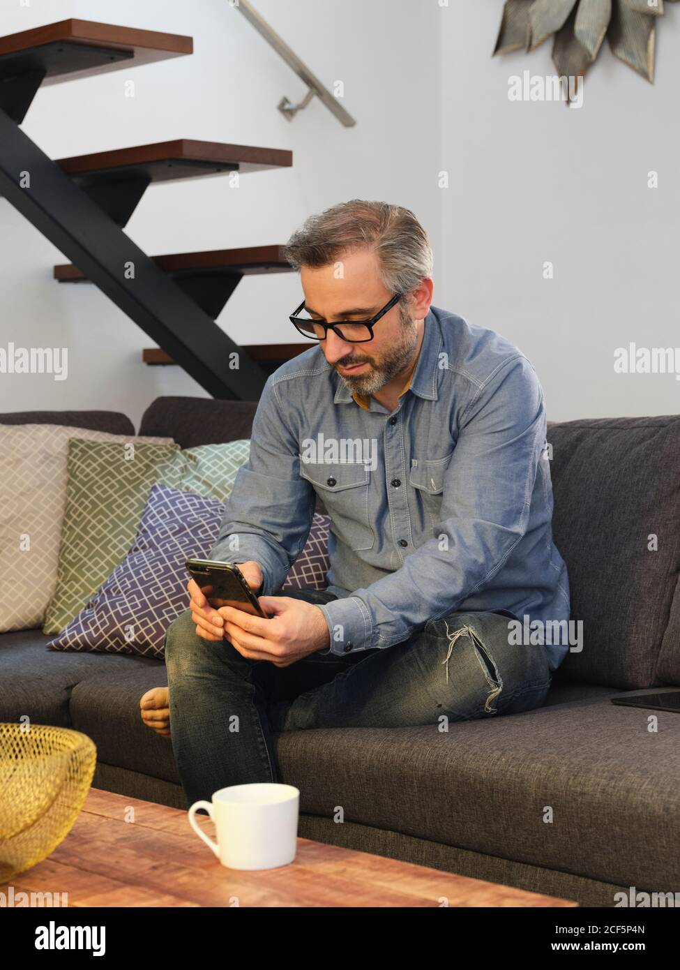Mann, der zu Hause vom Sofa aus telefoniert Entspannt zu Hause Stockfoto