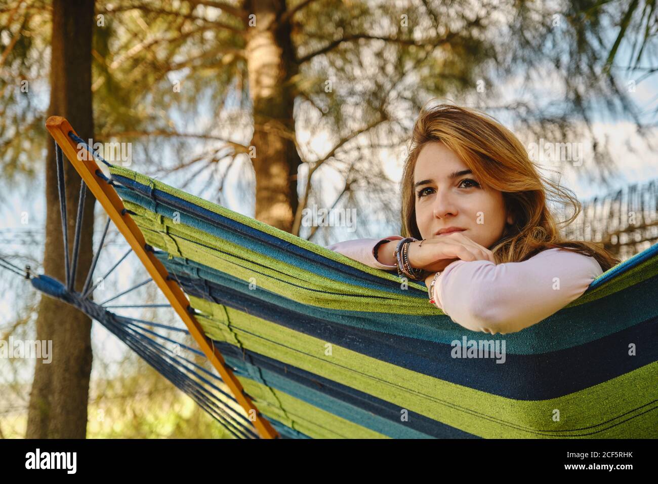 Ruhige Frau in zwanglosem Outfit in Hängematte im Innenhof sitzen Und genießen Sie den Sommerurlaub Stockfoto