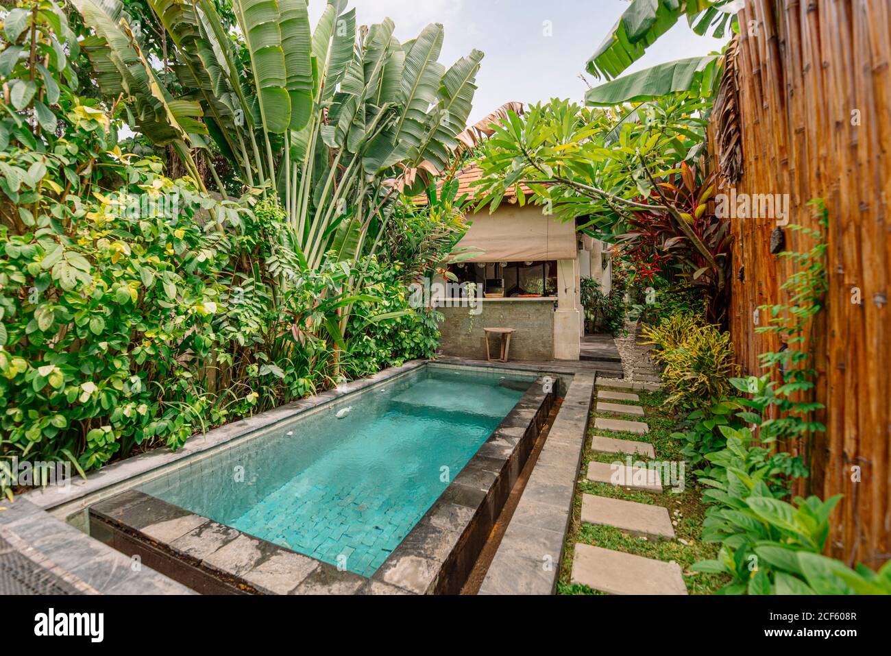 Gemtlicher Innenhof mit Pool, umgeben von tropischen Pflanzen und Bambus  Zaun in Bali Stockfotografie - Alamy