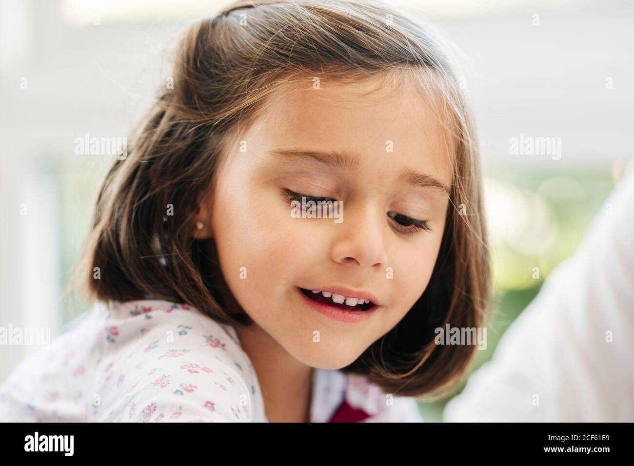 Liebenswert lächelnd kleines Mädchen mit dunklen Haaren Reichweite aus der Hand Während der Teilnahme an der Spielaktivität mit Crop Person Stockfoto