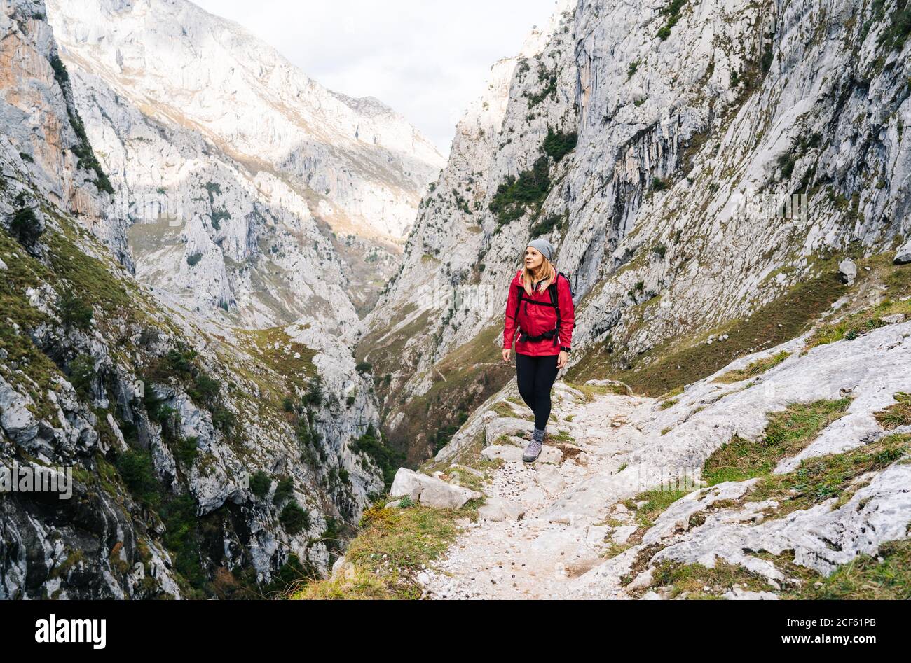 Aktive Frau Wanderer in roter Jacke mit schwerem Rucksack zu Fuß auf den Berg in den Gipfeln Europas, Asturien, Spanien Stockfoto