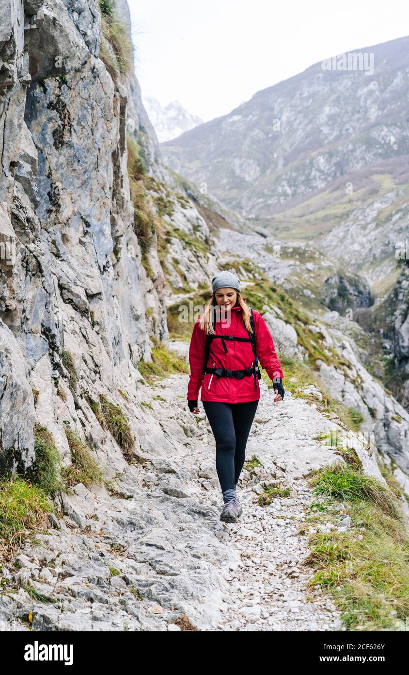 Aktive Frau Wanderer in roter Jacke mit schwerem Rucksack zu Fuß auf den Berg in den Gipfeln Europas, Asturien, Spanien Stockfoto